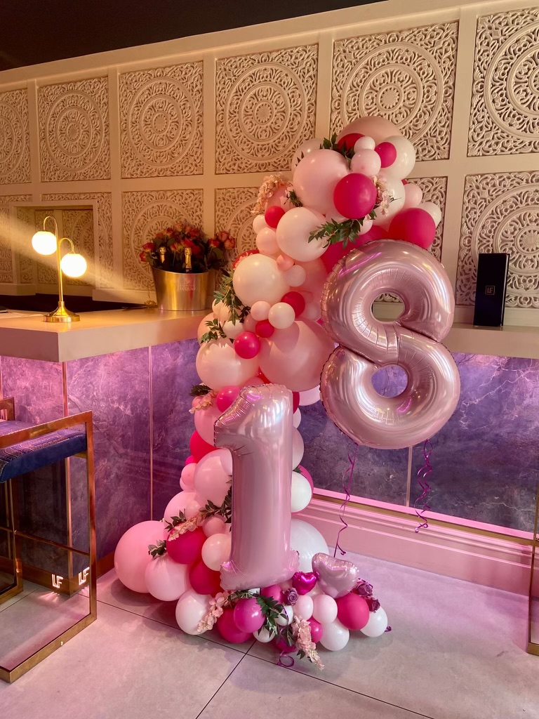 A balloon arch and giant 18 balloons against Le Fleur's ornate panelling