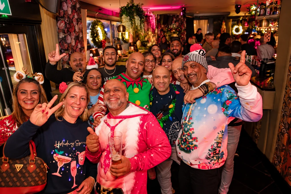 A crowd in Christmas jumpers celebrating together on the dance floor
