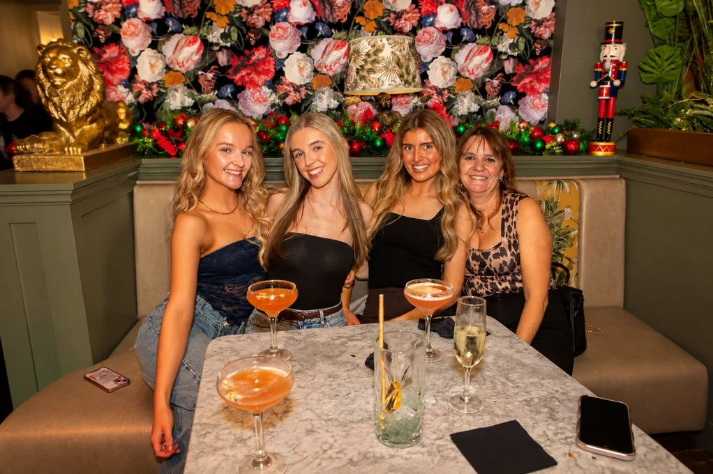 Four friends with cocktails at a table under the tree and nutcrackers