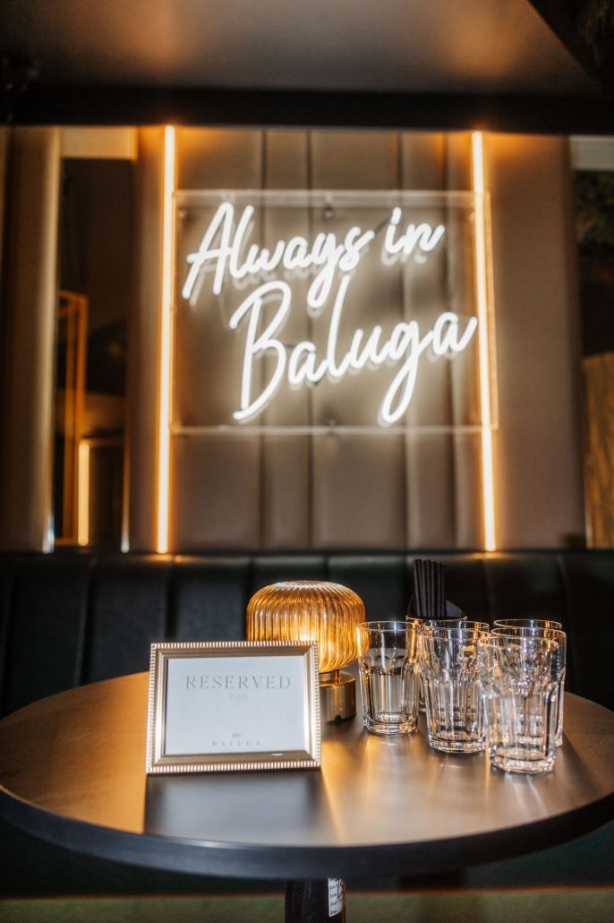 A reserved VIP table beneath the Always in Baluga neon sign